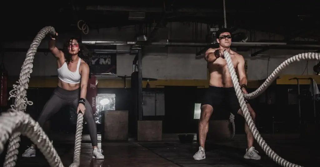 Two people engage in a powerful indoor battle rope workout, showcasing strength and energy.